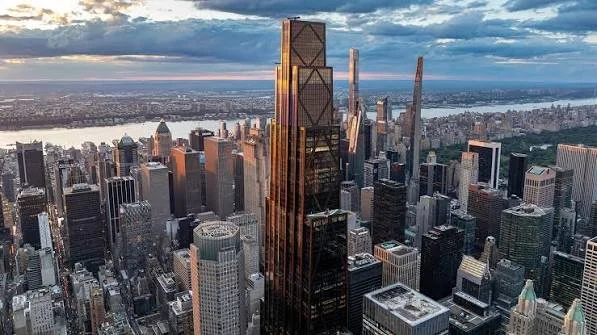 Aerial view of Manhattan skyline at sunset with tall skyscrapers and the Hudson River in the background.