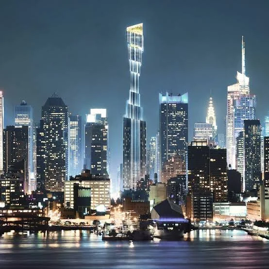 Nighttime cityscape of New York City skyline with illuminated skyscrapers reflecting on the water.