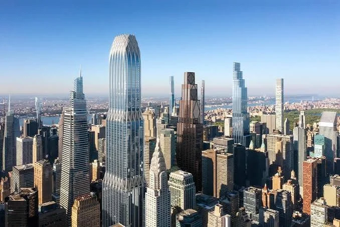 Aerial view of a city skyline with tall skyscrapers, including the distinctive Twisting Building, under a clear blue sky.
