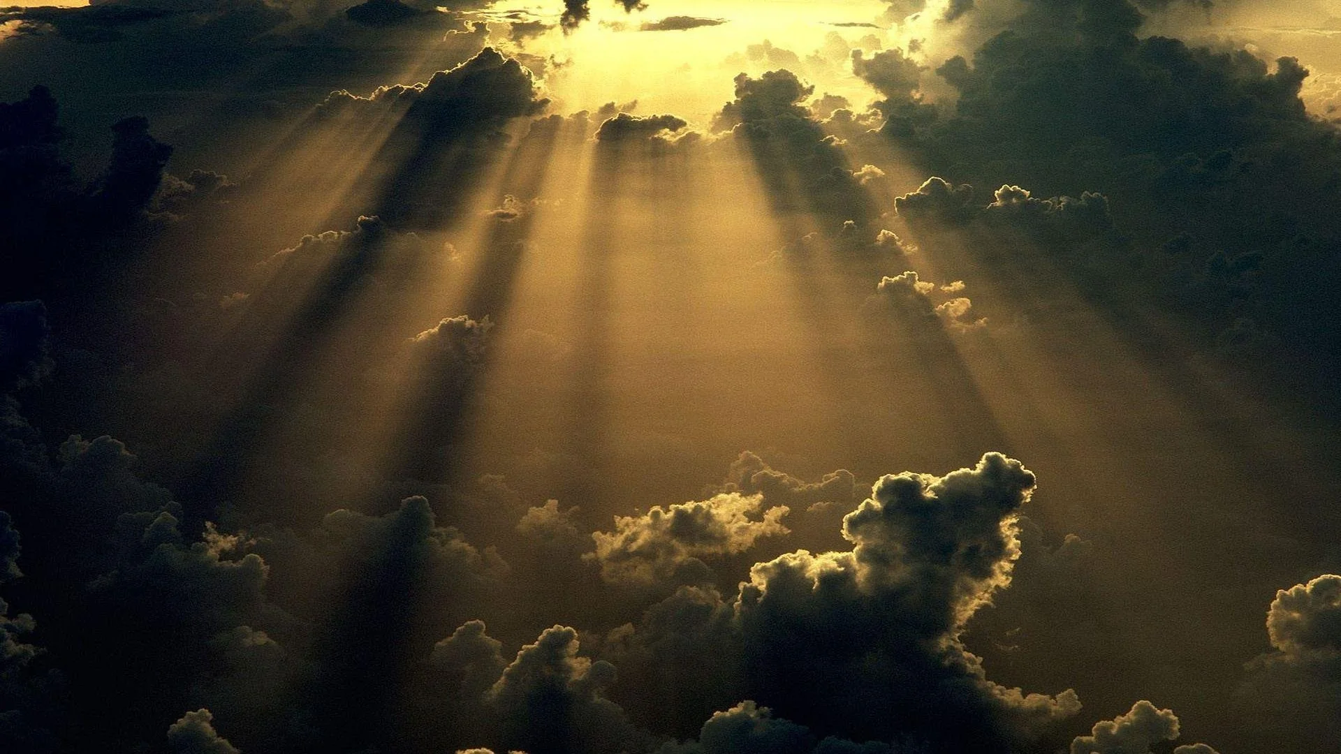 Sun rays breaking through dark clouds in the sky.