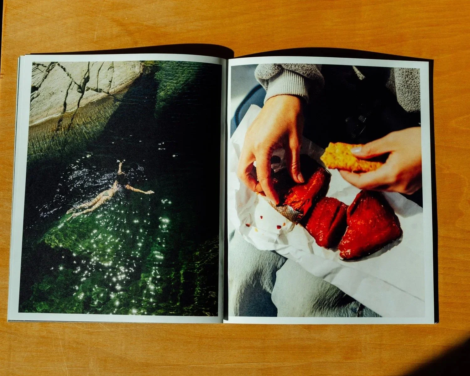 Open magazine showing a person eating smoked fish and bread, with a water scene on the opposite page.