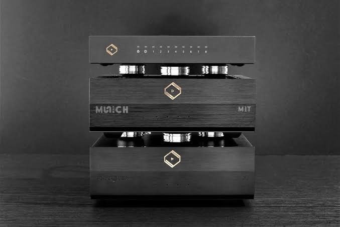 A close-up of a high-end audio component, possibly a stereo amplifier or a preamplifier, showing a sleek black design with gold accents and control buttons or indicator lights on the top panel.