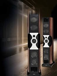 Two tall floor-standing speakers, one black and one brown, in a modern interior space.