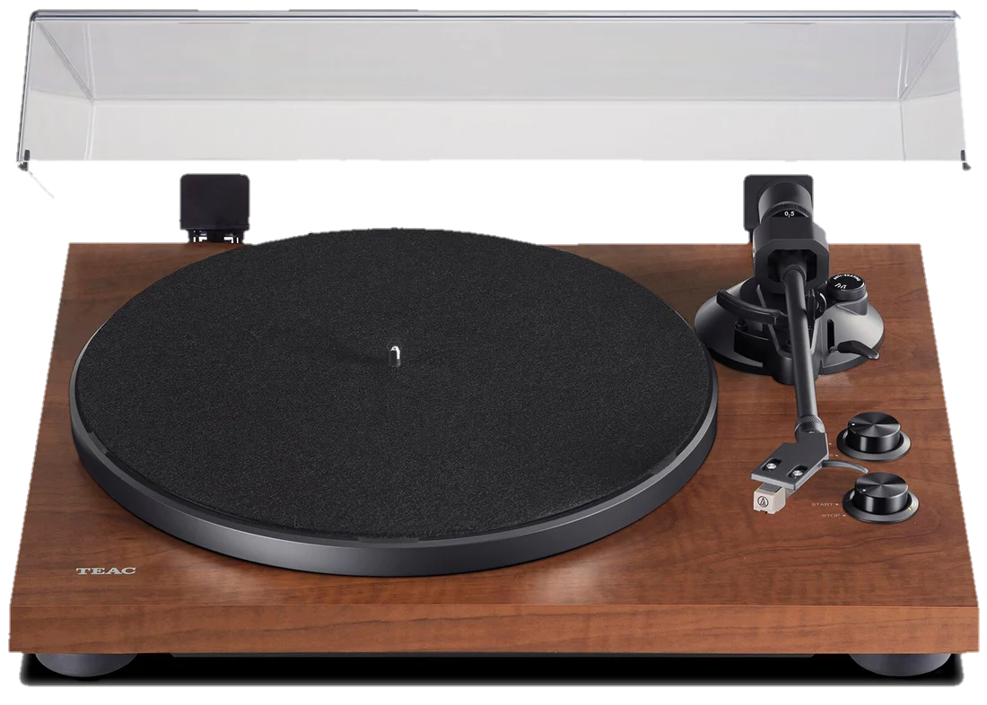 A vintage Teac turntable with a wooden finish, black platter, tonearm, and control knobs on a wooden surface with a shielding cover in the background.