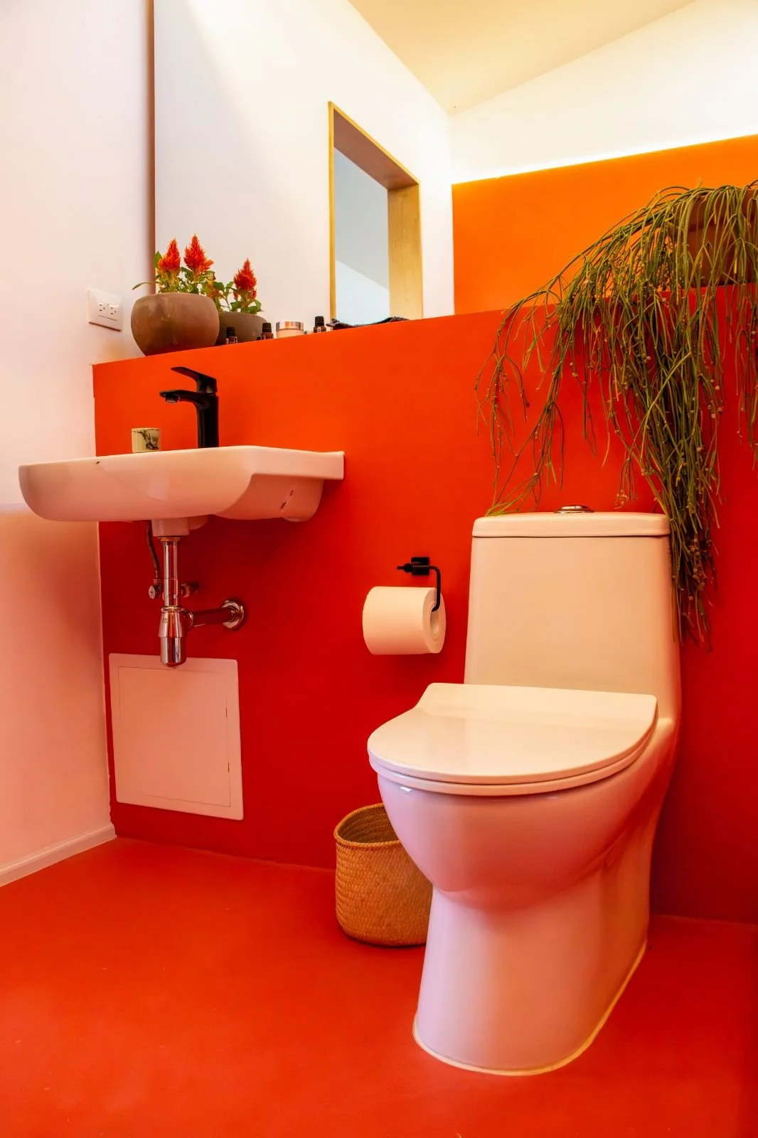 Baño de vivienda compacta en la naturaleza con acabado de resina epoxica en color naranja