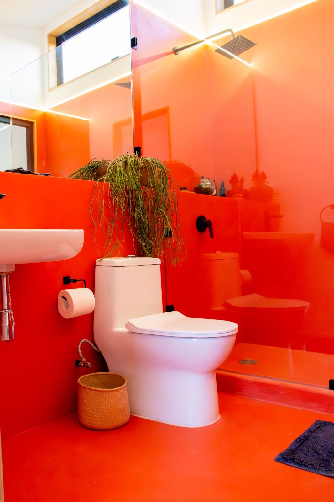 Baño de vivienda compacta en la naturaleza con acabado de resina epoxica en color naranja