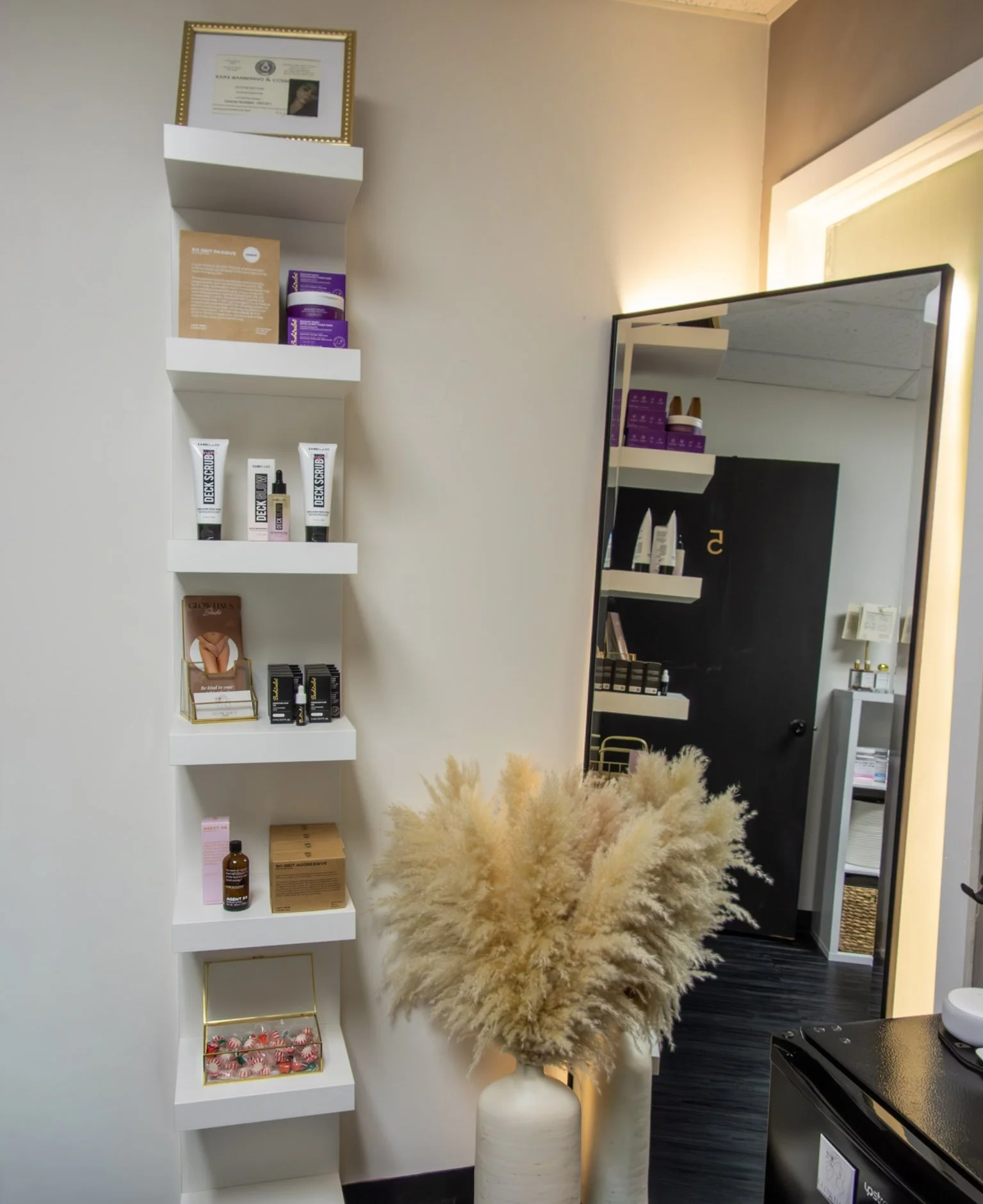 Modern esthetics studio featuring skincare products, a full-length mirror, and retail display shelves in a welcoming treatment space.