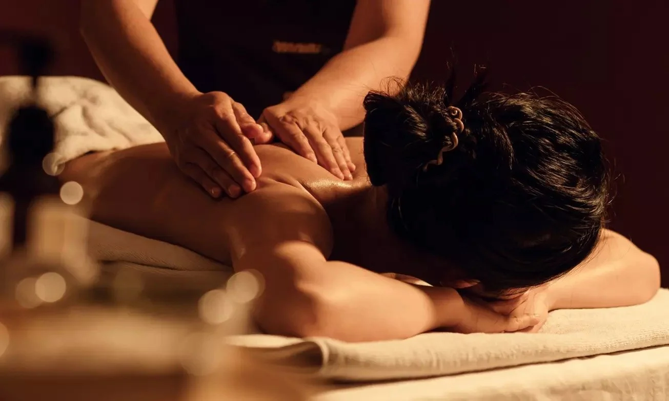 Une personne reçoit un massage dans un spa ou un centre de bien-être, allongée sur un lit de massage.