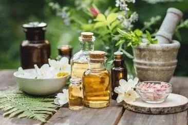 Vases et flacons d'huiles essentielles, mortier et pilon, fleurs fraîches, et bols dans un cadre naturel