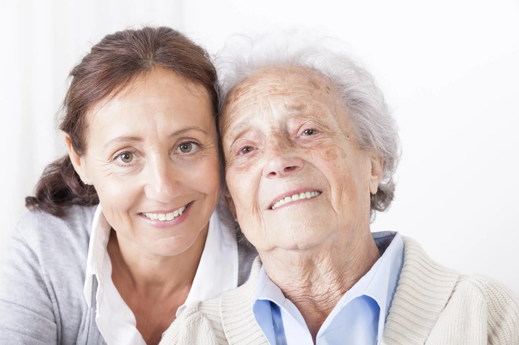 A woman and an elderly man smiling and close together against a white background.