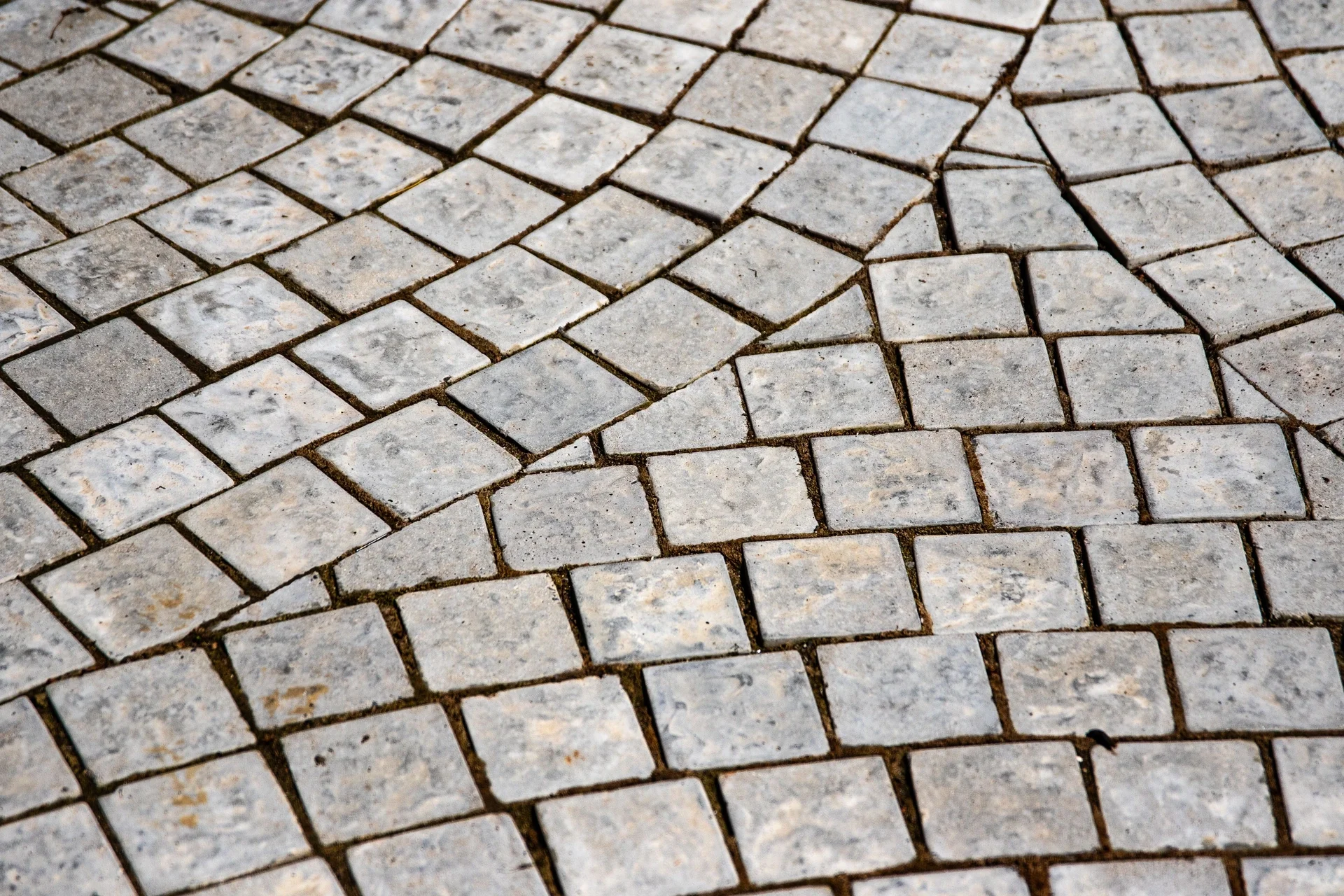 Close-up view of arranged small square and rectangular stone tiles forming a mosaic pattern on the ground.