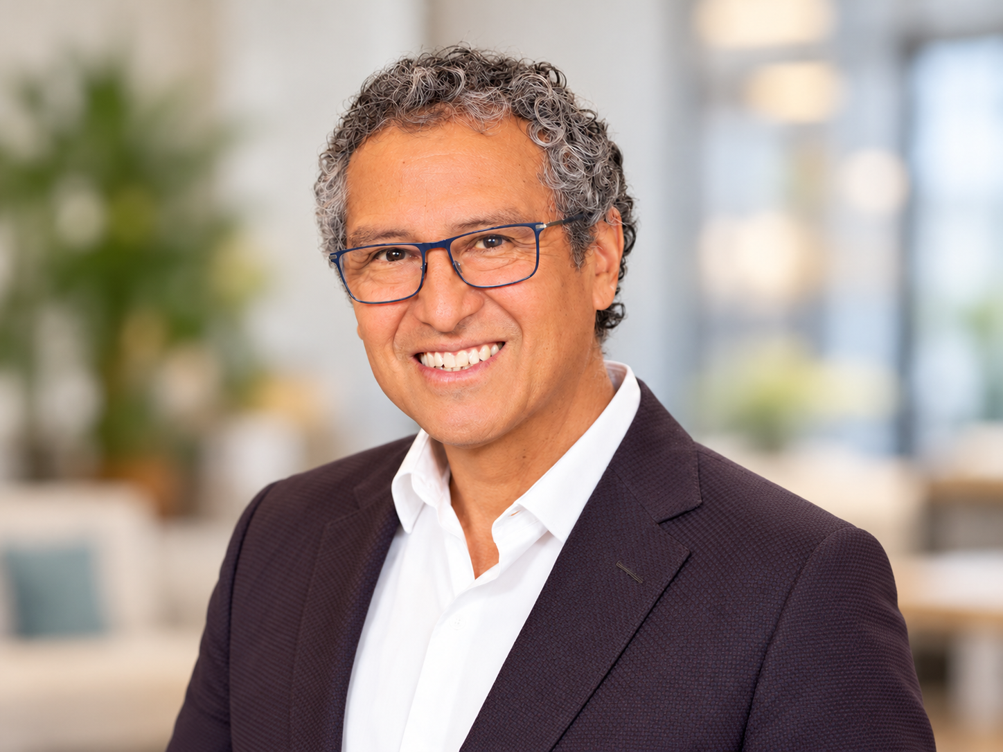 Professional portrait of a smiling man wearing glasses and a dark blazer, featured on SANT Language Studio's Spanish tutoring and language education website.