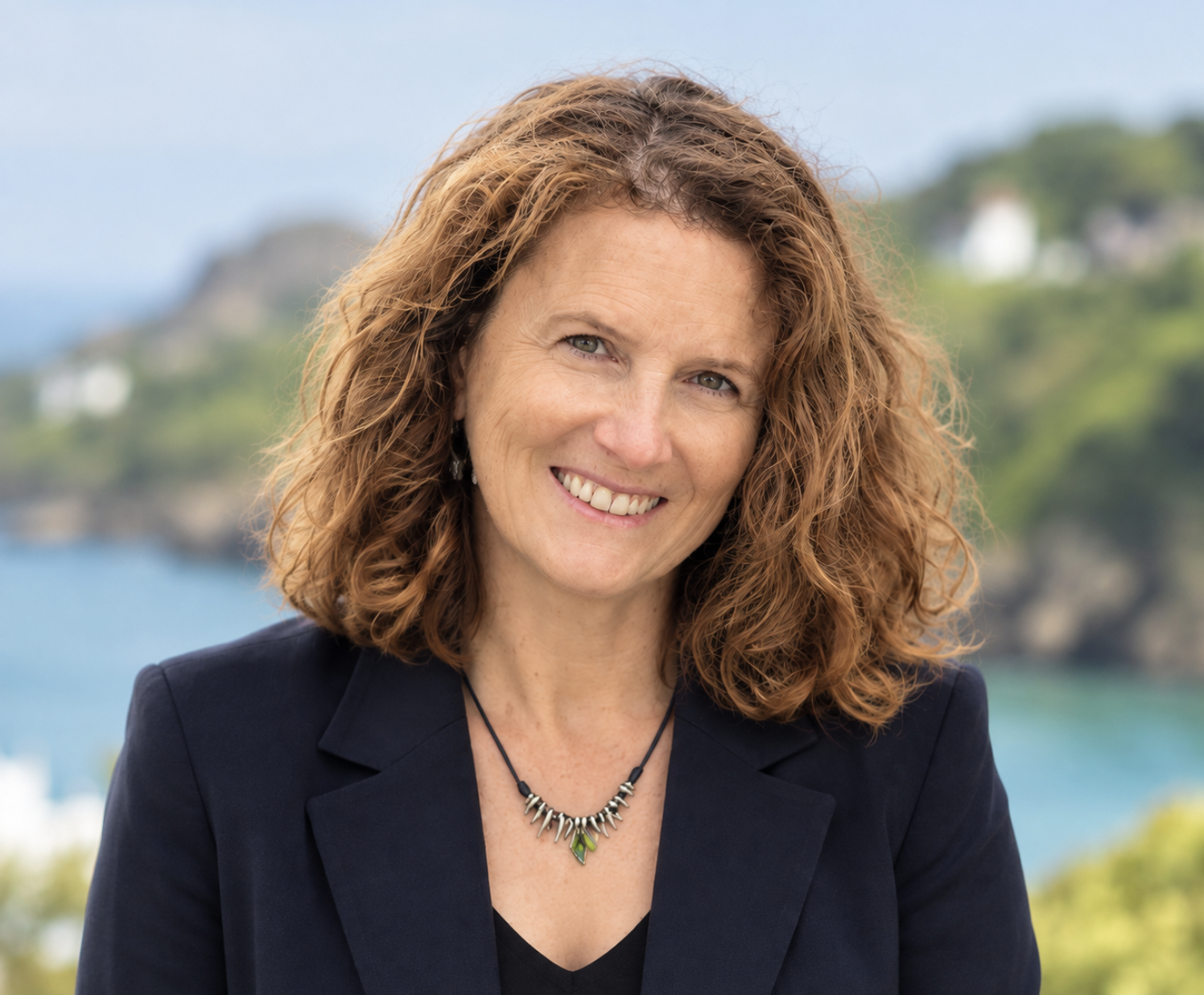Portrait of a smiling woman with curly red hair outdoors, featured on SANT Language Studio's online Spanish tutoring website.