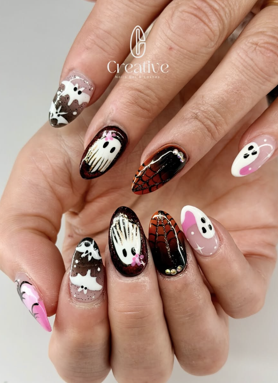 Nail art with Halloween-themed designs including ghosts, spiders, webs, and bats in black, white, pink, and orange colors.