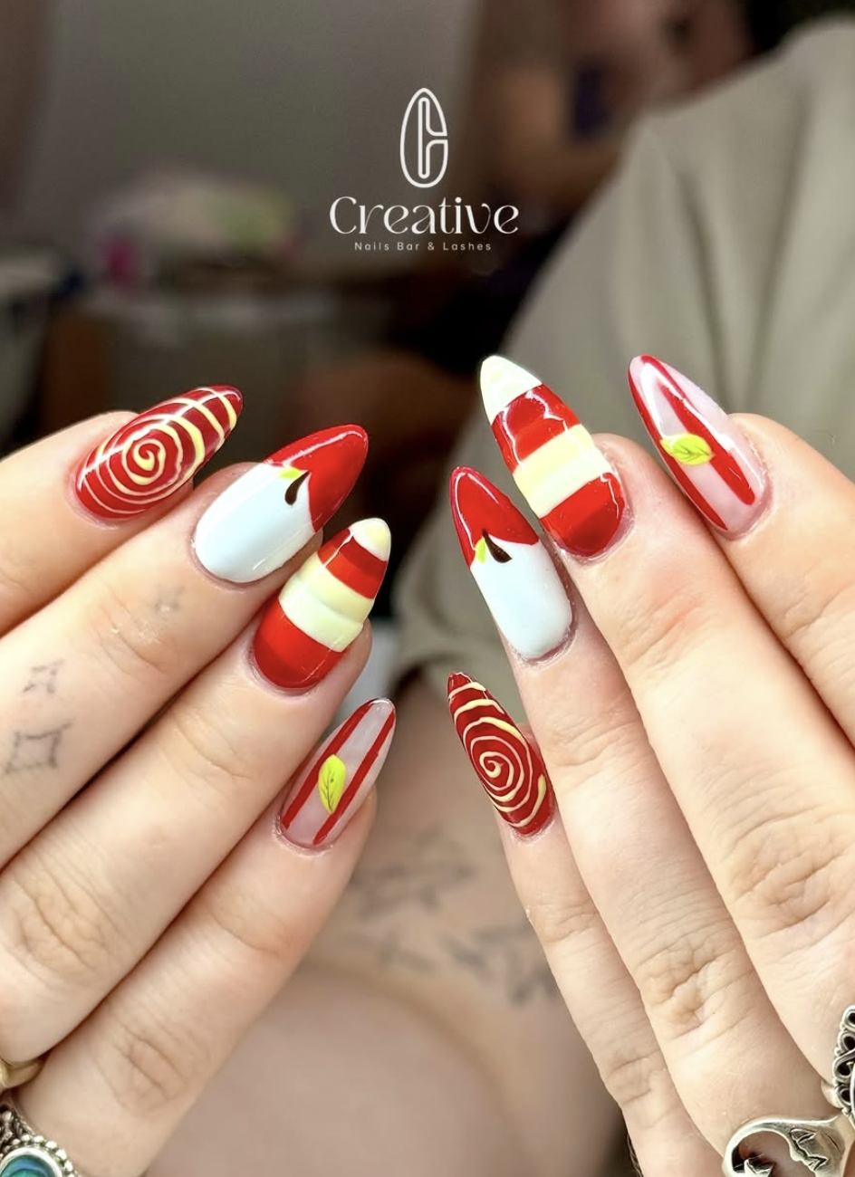 Nail art featuring red, white, and green stripes, swirls, and leaf designs.