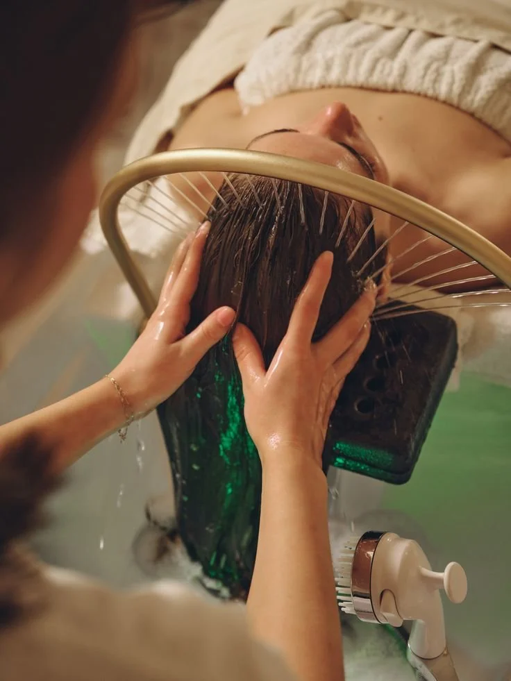 Person receiving a facial treatment with a device that has multiple metal prongs, while lying down with eyes closed at a spa or clinic.