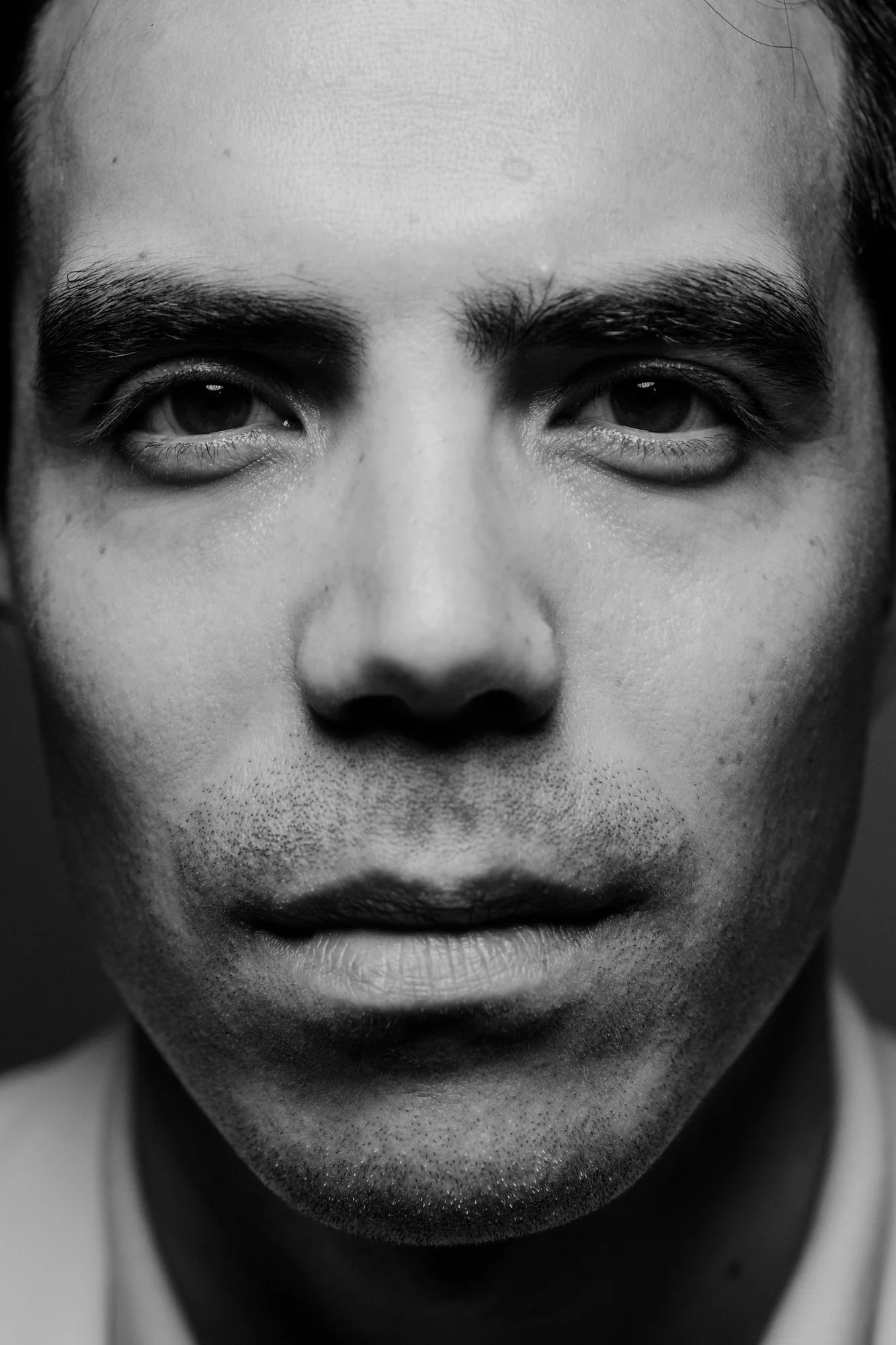 Close-up of a person's face in black and white, showing their eyes, eyebrows, nose, and mouth with a focused expression.
