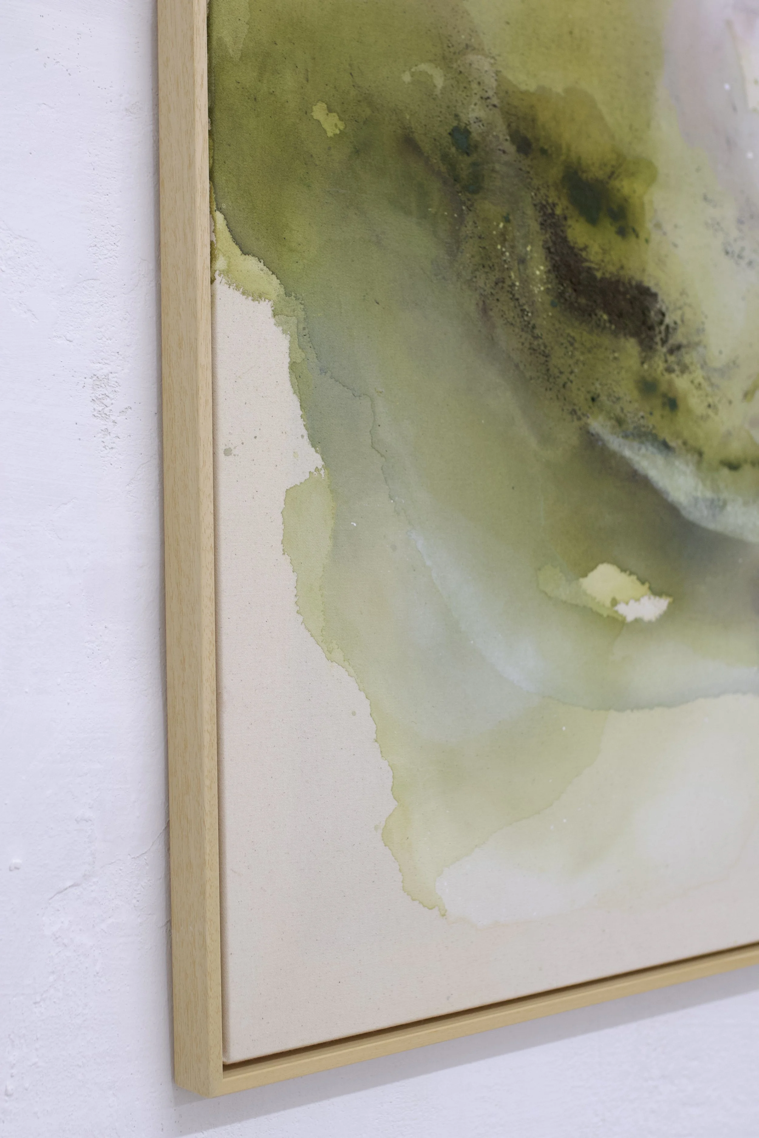 Aquarellgemälde mit grünen und gelblichen Farbverläufen, gerahmt in einen leichten Holzrahmen.