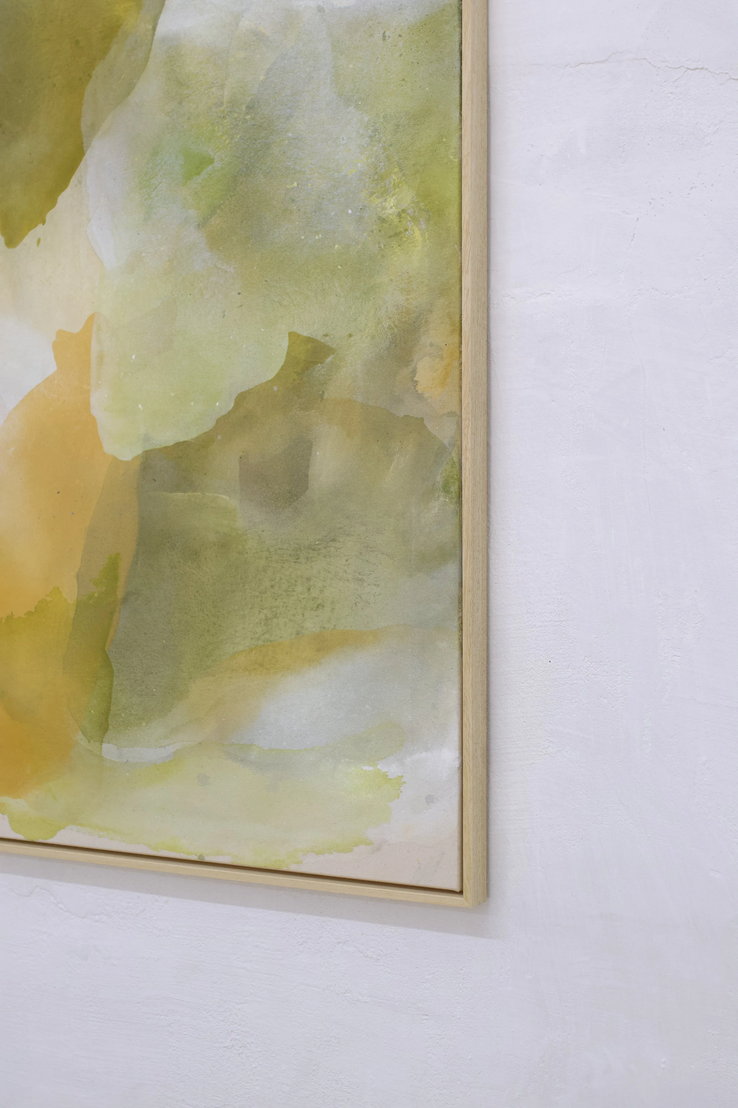Abstraktes, watercolorähnliches Bild in Grüntönen, eingerahmt mit Holz, an weißer Wand