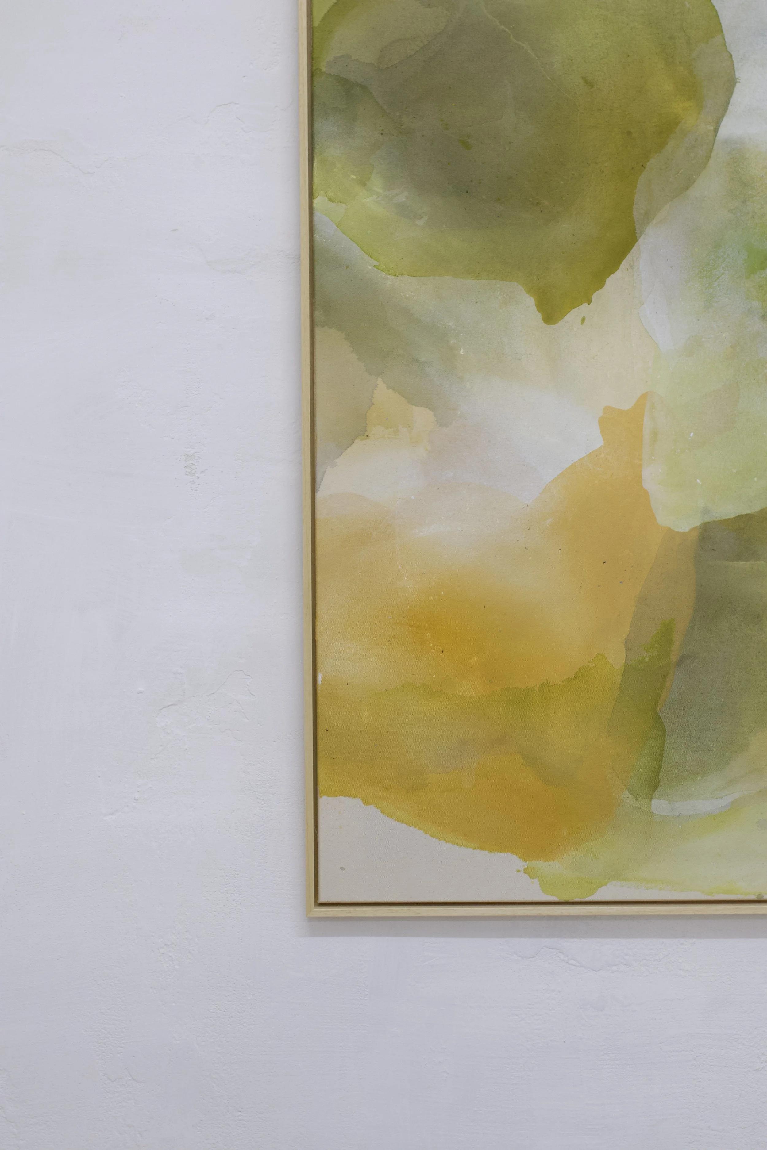 Aquarellgemälde mit verschiedenen gelben, grünen und braunen Farbtönen, eingerahmt und an einer weißen Wand aufgehängt.