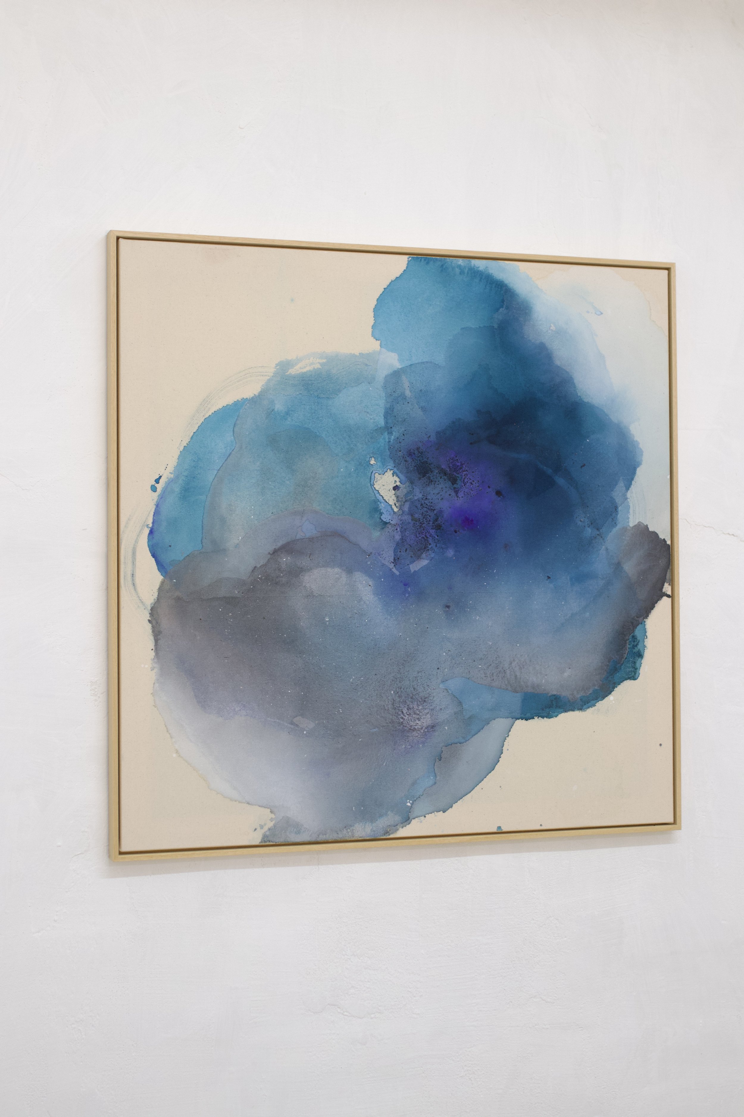 Abstraktes Gemälde mit blauen und grauen Wasserfarbtönen in Holzrahmen, hängend an einer weißen Wand.