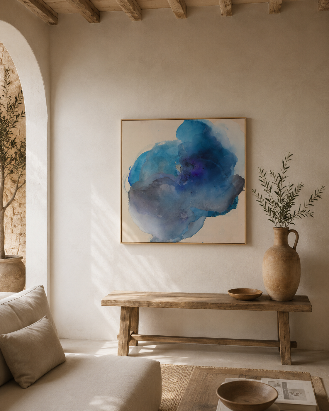 Innenraum mit weißer Wand, abstraktem blauen Gemälde, Holztisch, einer Vase mit grünen Zweigen, einem Sofa und einem Buch.