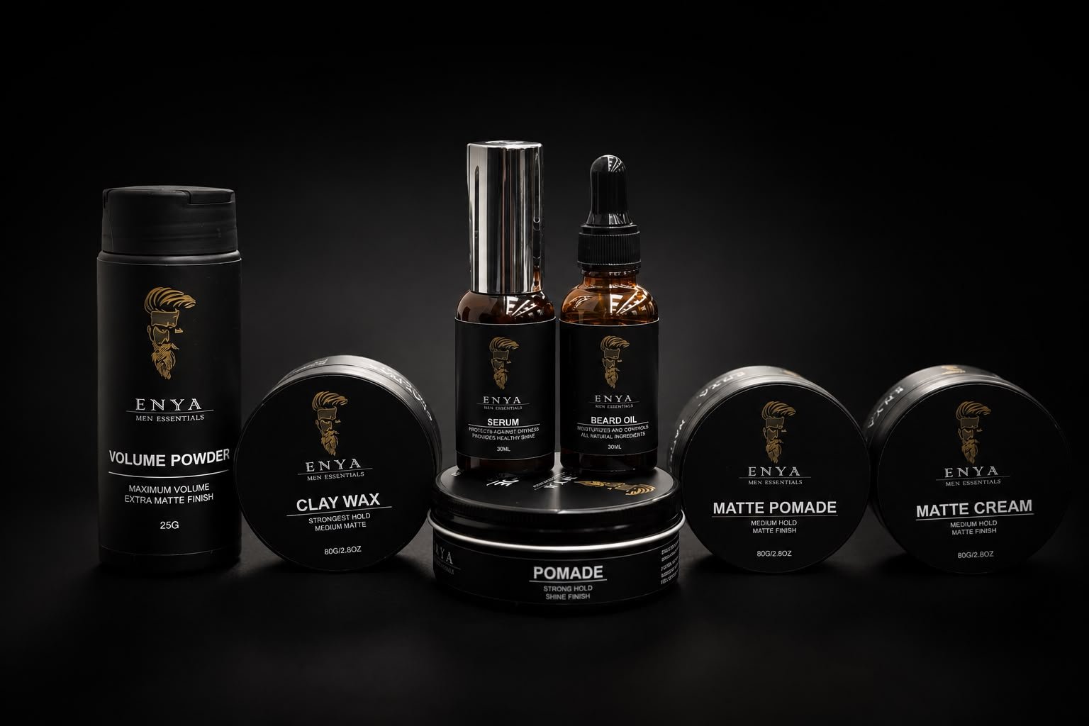 Collection of black grooming products for men with gold logo, including volume powder, clay wax, pomade, matte pomade, matte cream, serum, and beard oil, arranged on black surface with dark background.