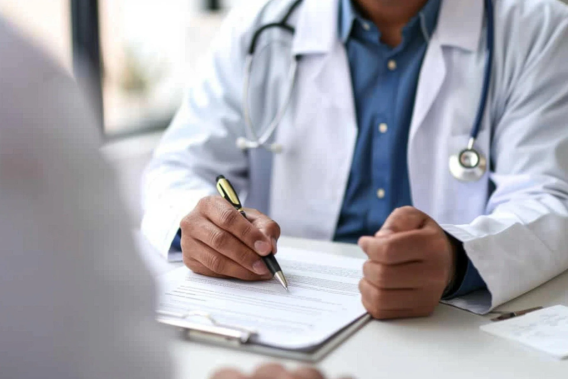 A doctor in a white coat and stethoscope writing on a clipboard.