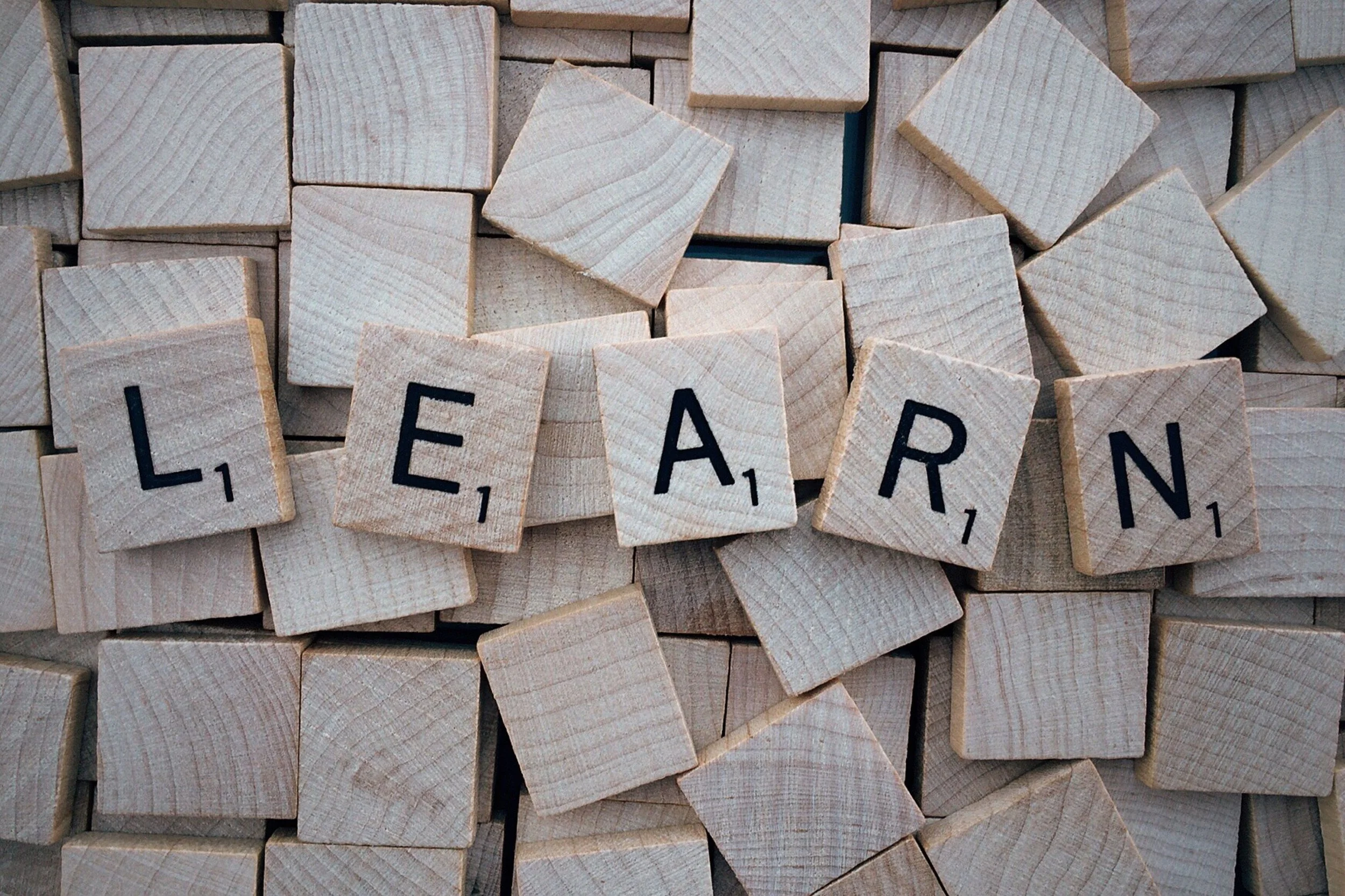 A close-up of numerous Scrabble tiles spelling out the word "LEARN" on a flat surface.