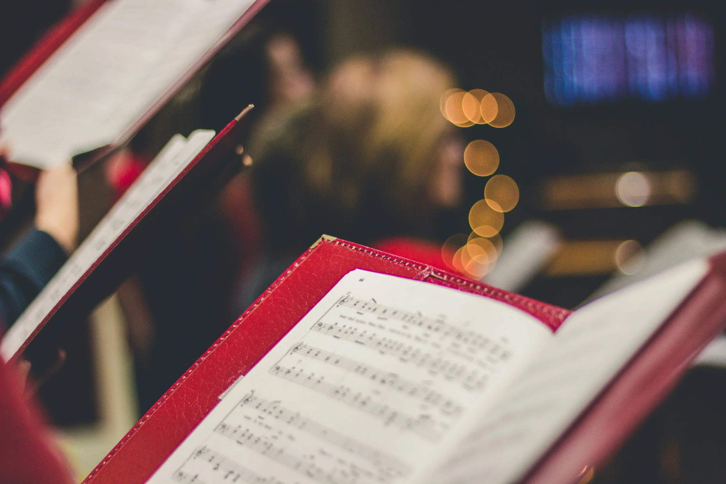 Singers holding red score folders during an ensemble rehearsal or performance.