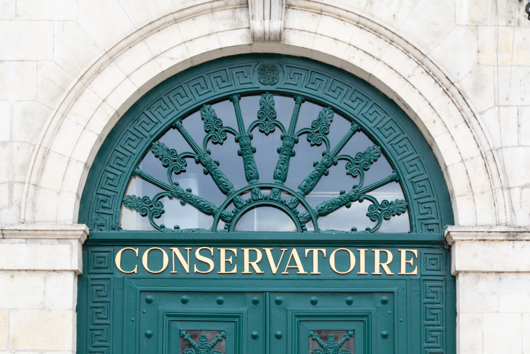 Ornate entrance door of a conservatoire with gold lettering and decorative ironwork.