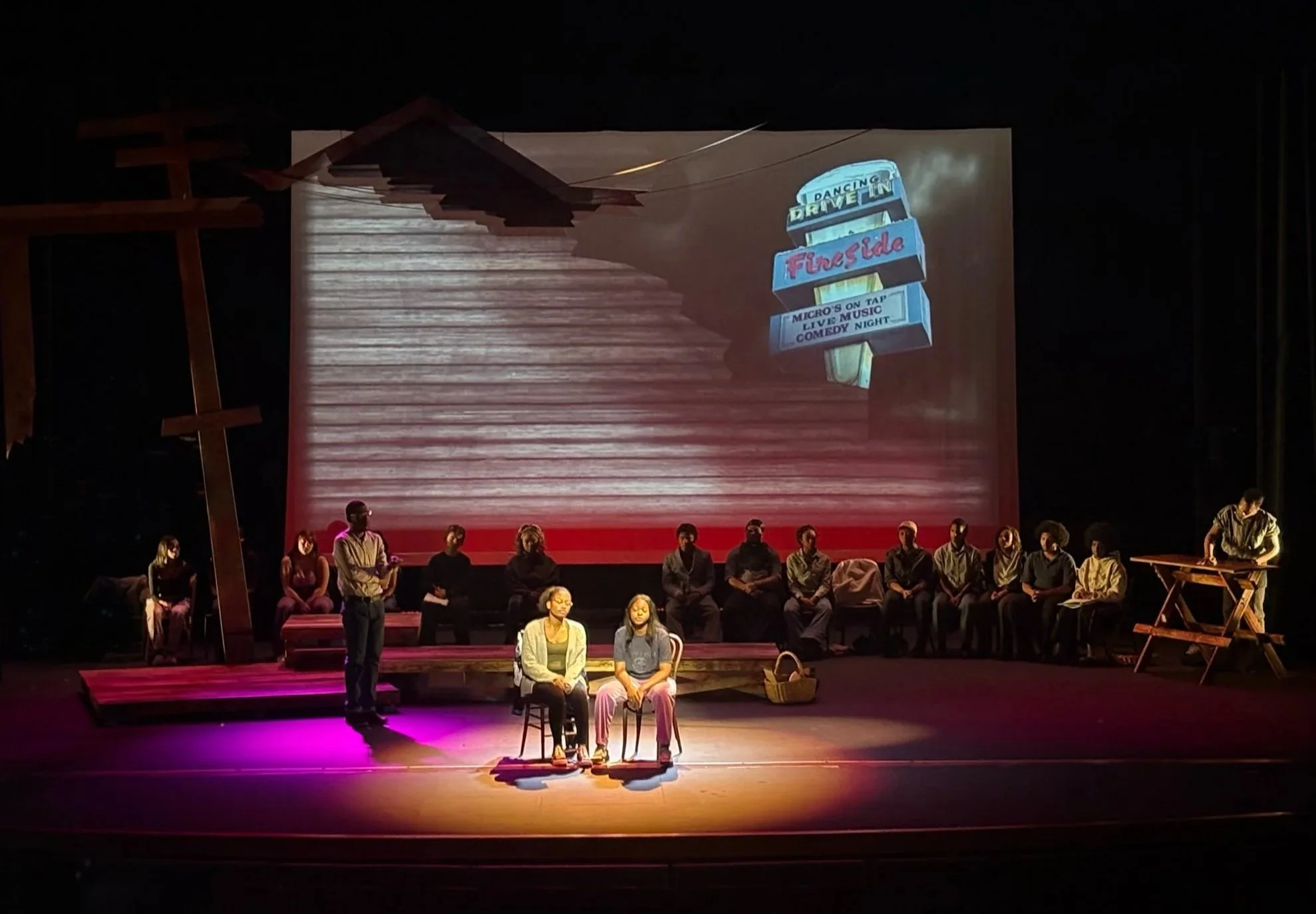 Projection design backing a spotlit scene for the Fireplace gay bar in the play “The Laramie Project” by Moises Kaufman and the Tectonic Theater Project