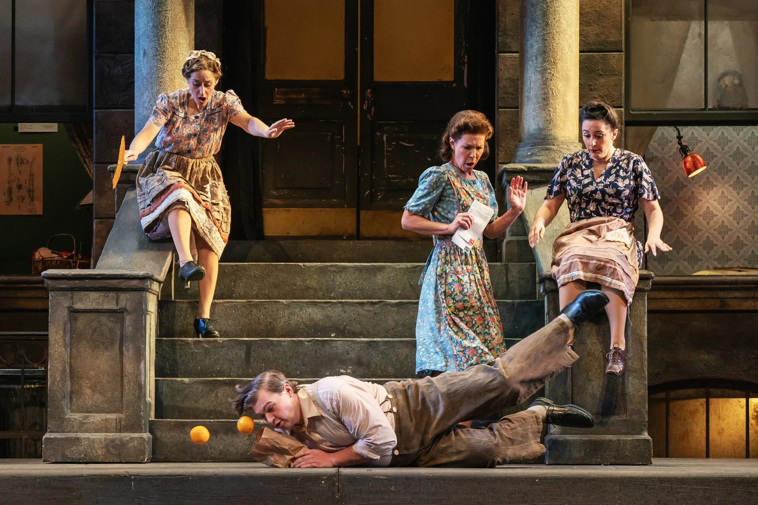 Shot of a singer falling with oranges on the front stoop of an apartment building in the opera “Street Scene”