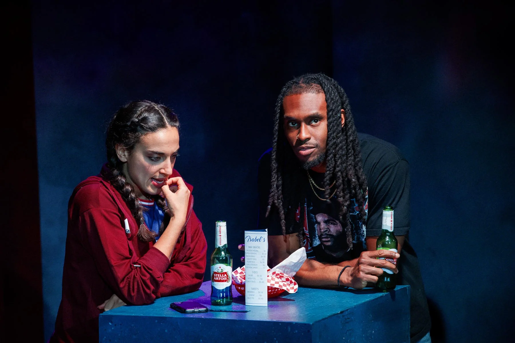 The bar featuring a menu, food, and drink props in the play “American Fast” by Kareem Fahmy