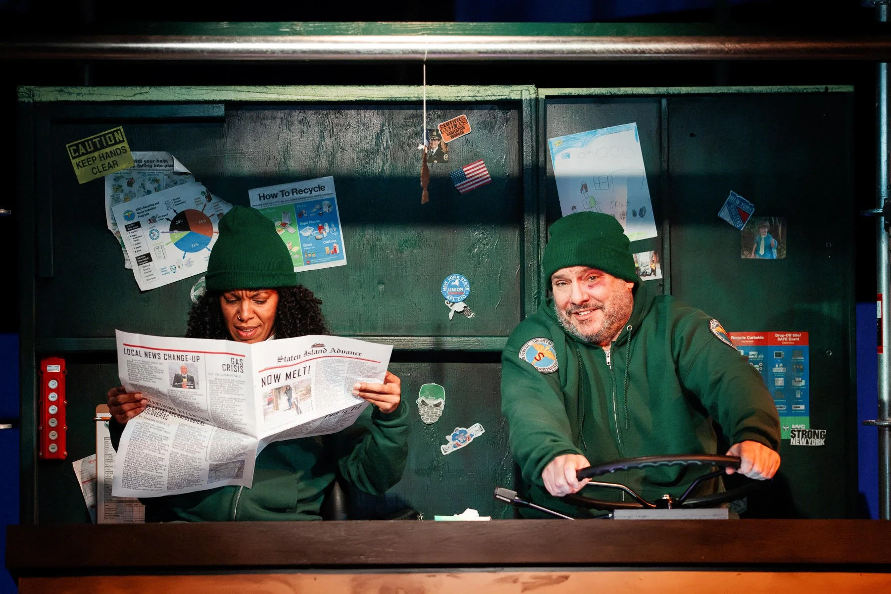 The actors in the truck cabin reading a graphic designed prop paper during the play “The Garbologists” by Lindsay Joelle