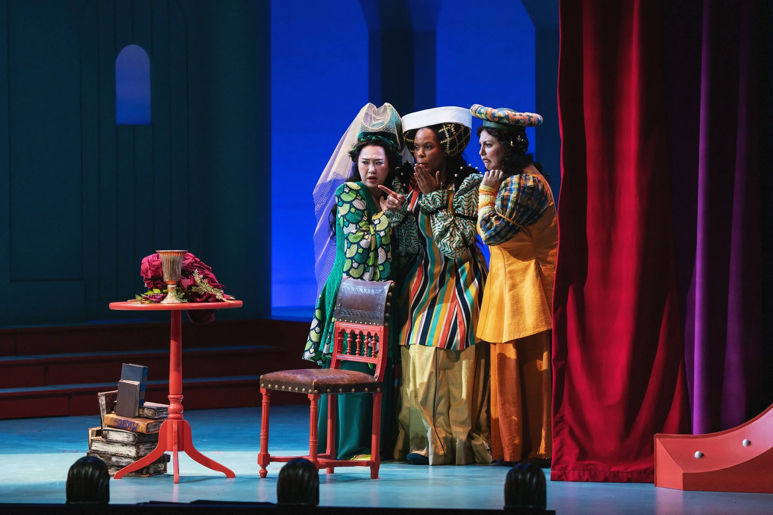 A shot of the ladies in waiting in the dressing room set of the opera “Once Upon a Mattress,” featuring furniture and a book sculpture