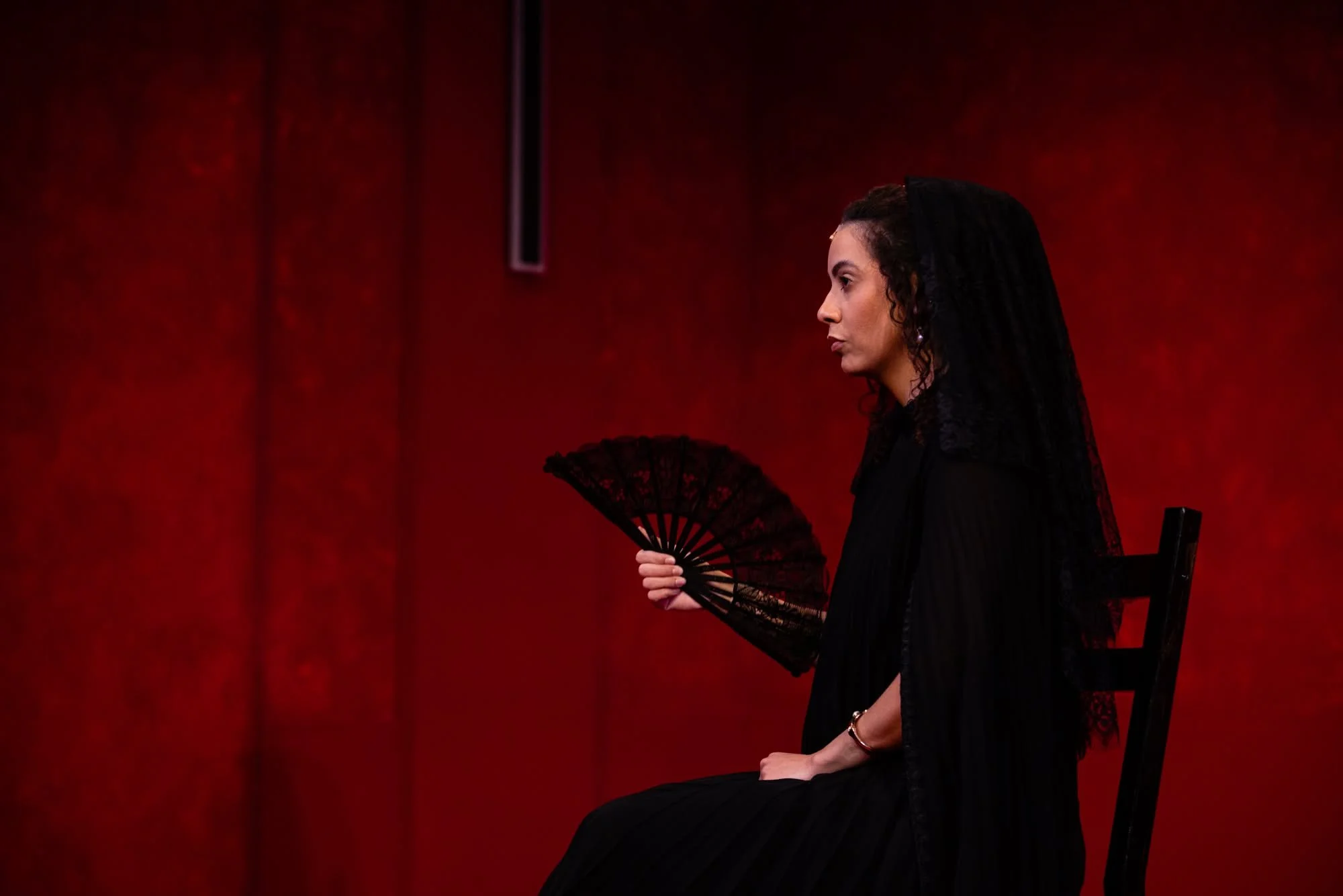 Close-up of an actress with a fan on a chair for the play “La Casa de Bernarda Alba” by Federico García Lorca
