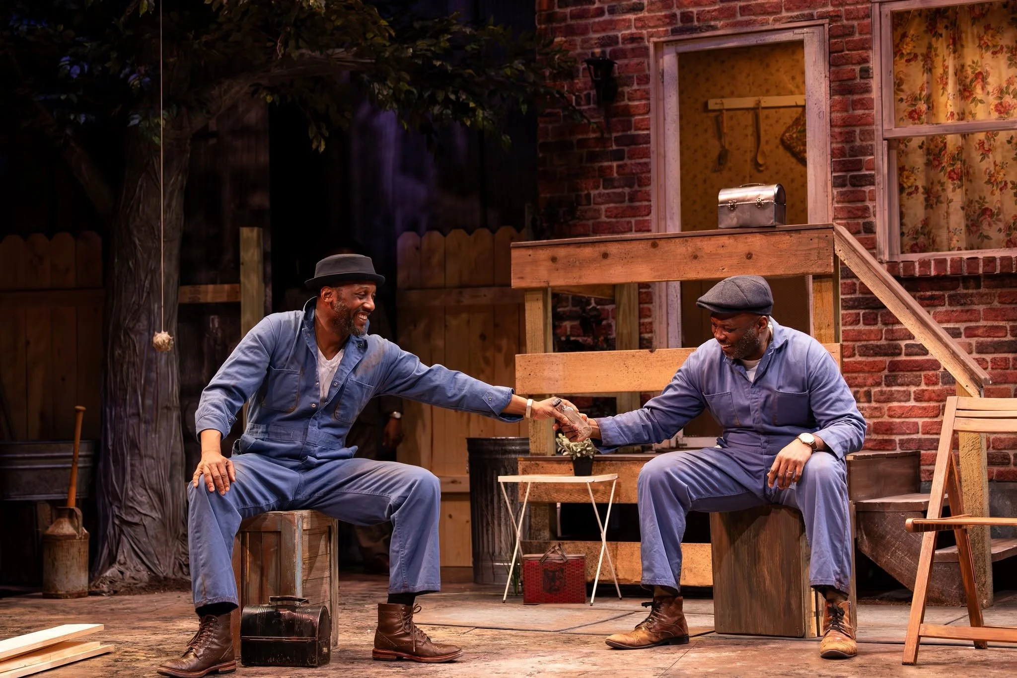 Troy and Bono sitting in the yard and drinking after work during the play “Fences” by August Wilson