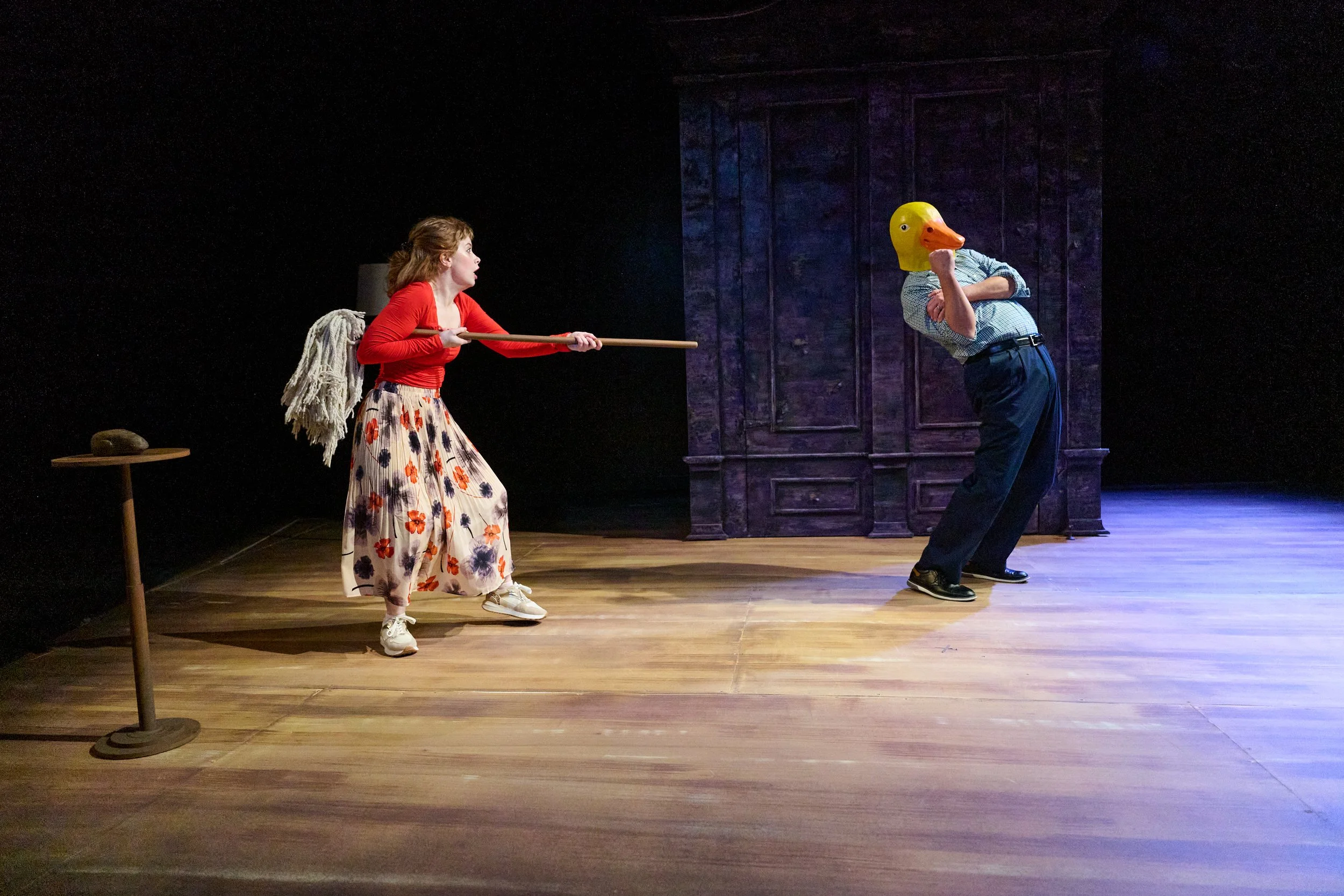 A woman pointing a mop at a man with a duck mask in the North American premiere of “Lie Low” by Ciara Elizabeth Smyth