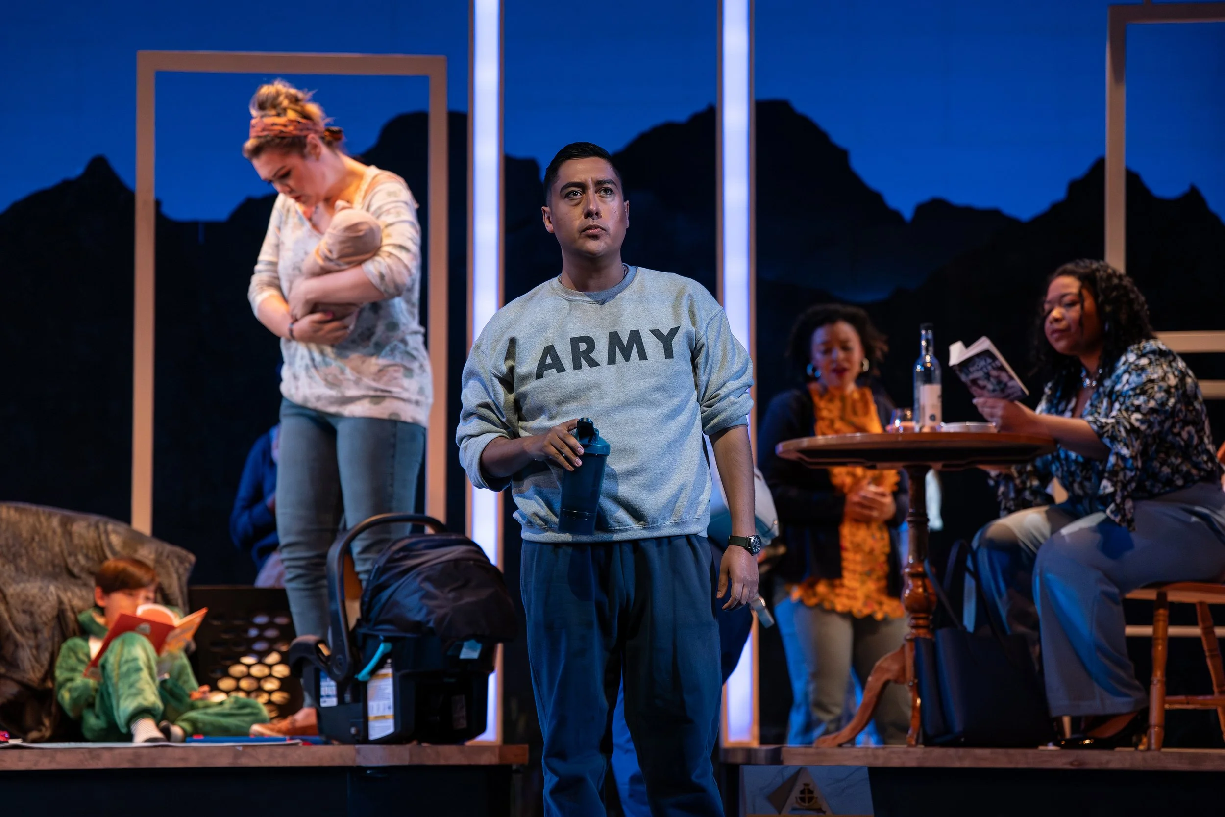 An army man standing downstage of a house in the opera “The Knock”