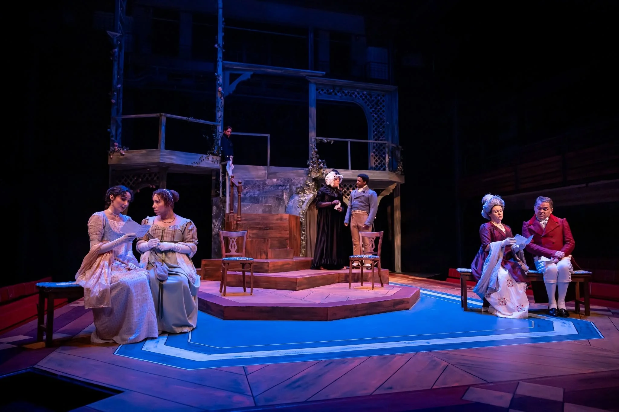 Actors at a concert sitting on upholstered chairs and benches with designed programs in the play “Persuasion” by Jane Austen, adapted by Sarah Rose Kearns
