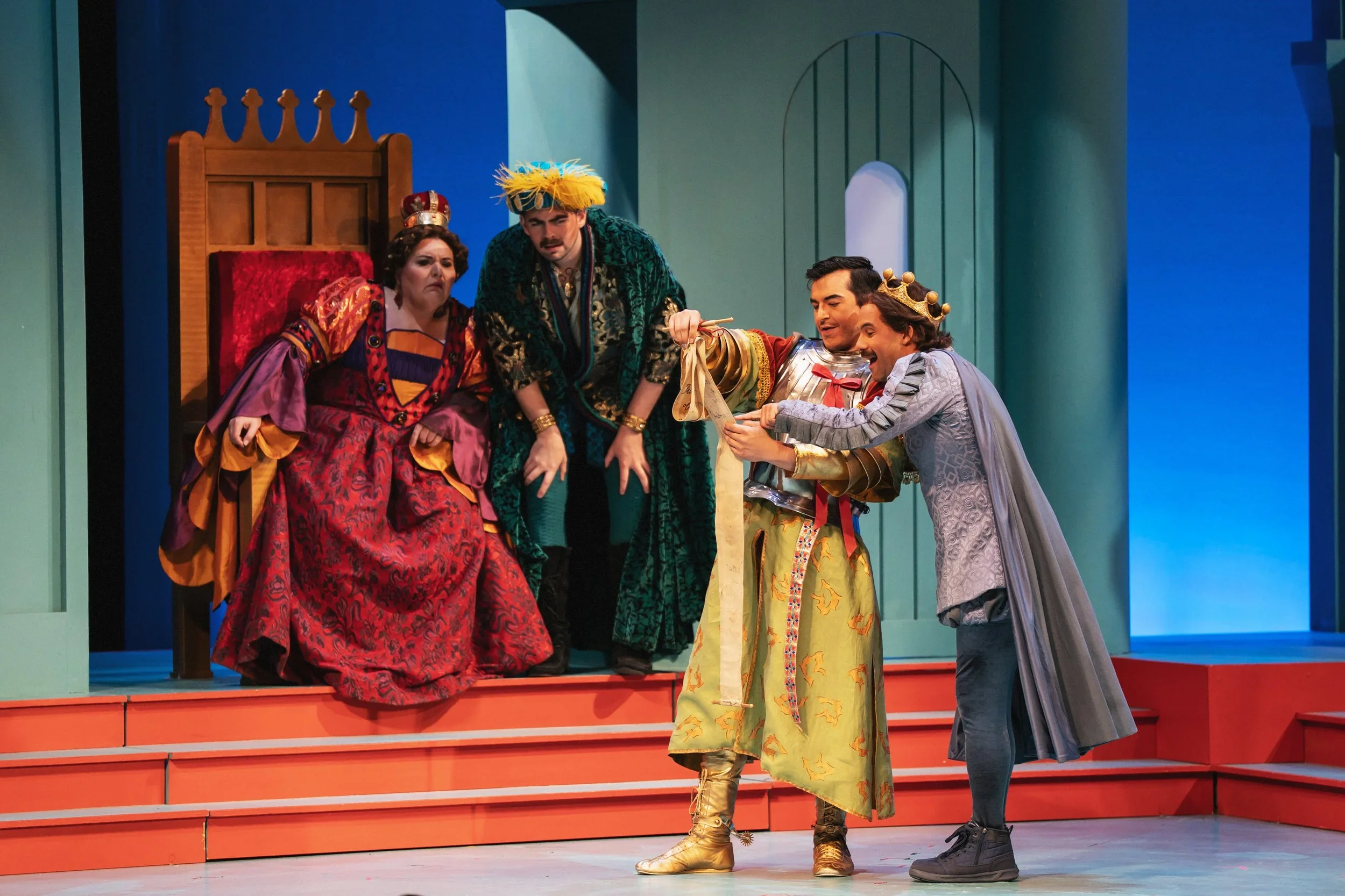 The queen on the throne and the prince reading a very long scroll in the opera “Once Upon a Mattress”