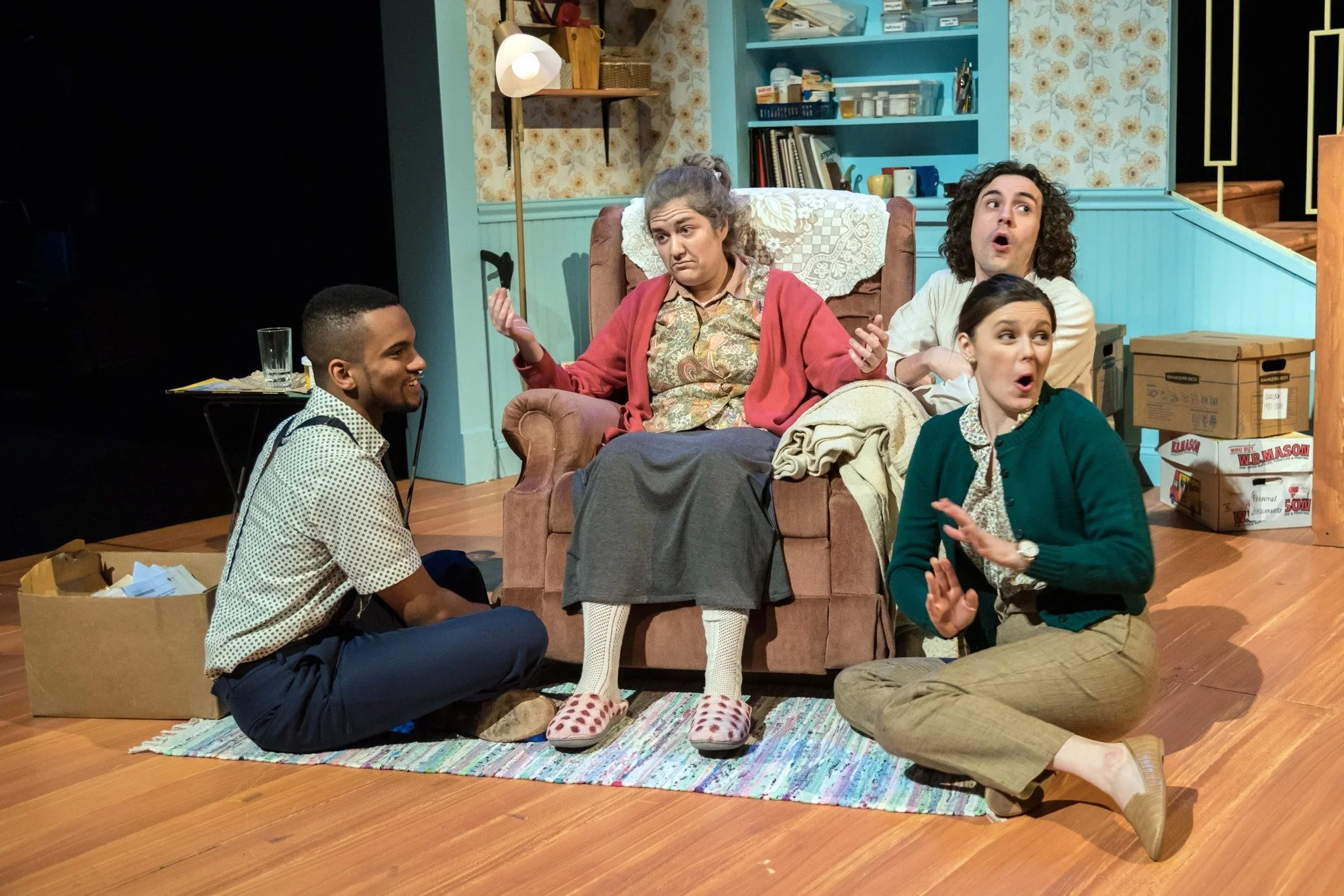 Actors gathered in the living room of the scenic design for the play “Well” by Lisa Kron