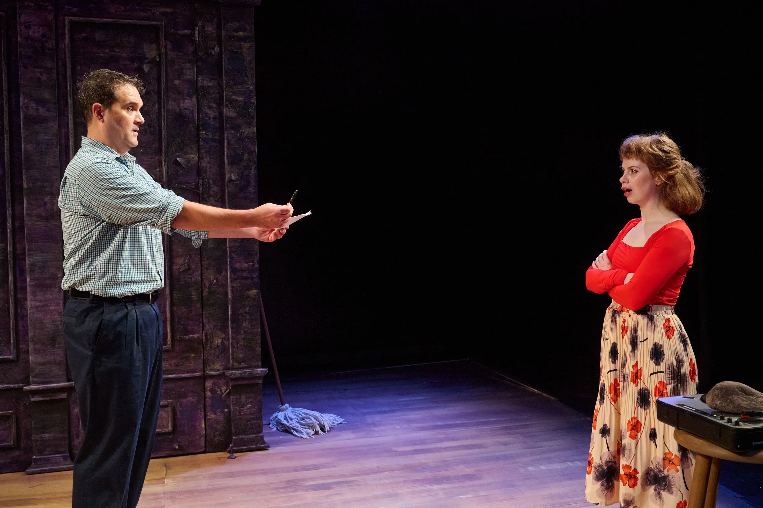 The actor holding the witness statement and pen onstage during the North American premiere of “Lie Low” by Ciara Elizabeth Smyth