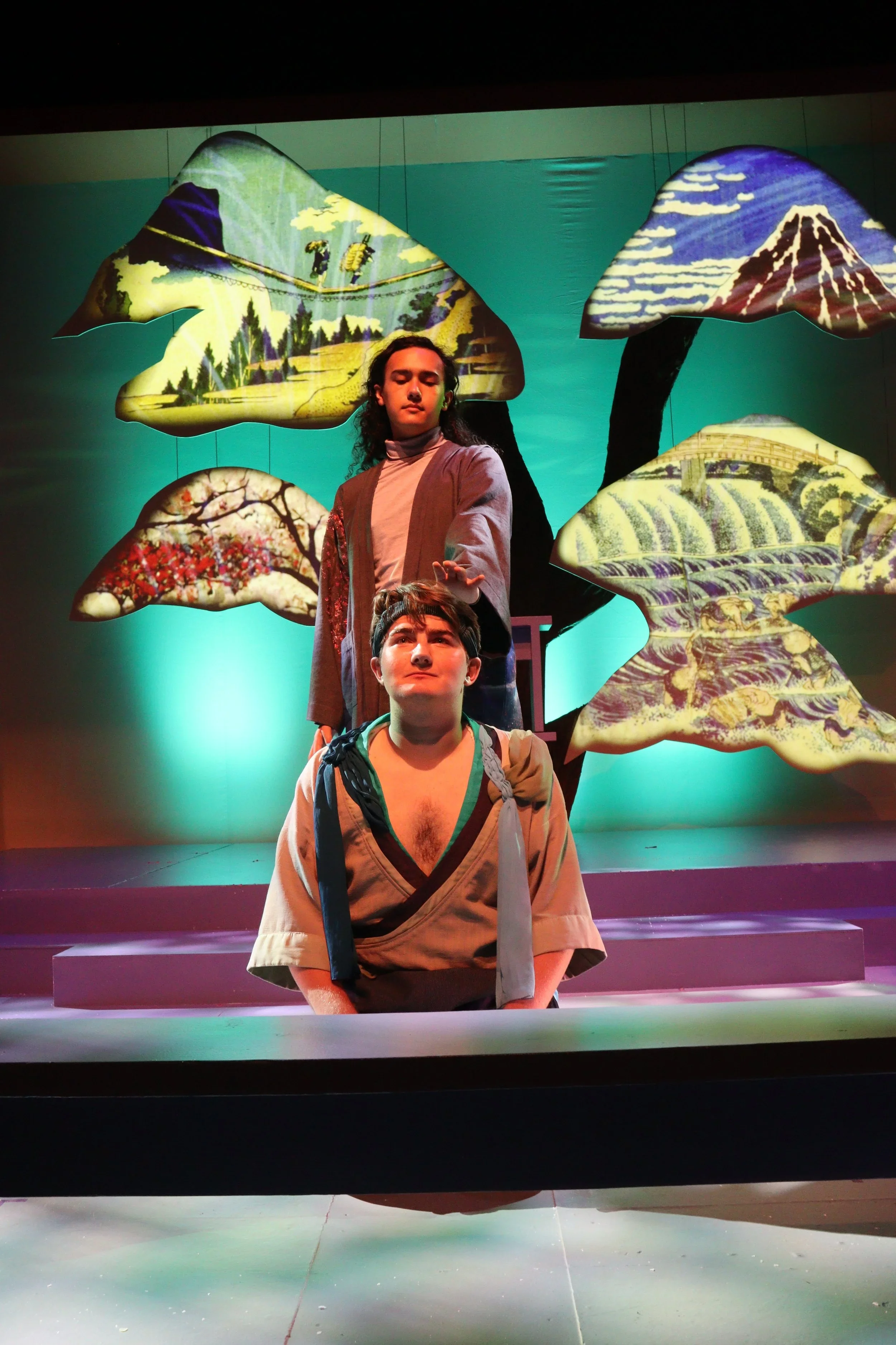 Close up of two actors in front of the Noh style tree on the upstage part of the set for the play “The Long Christmas Ride Home” by Paula Vogel