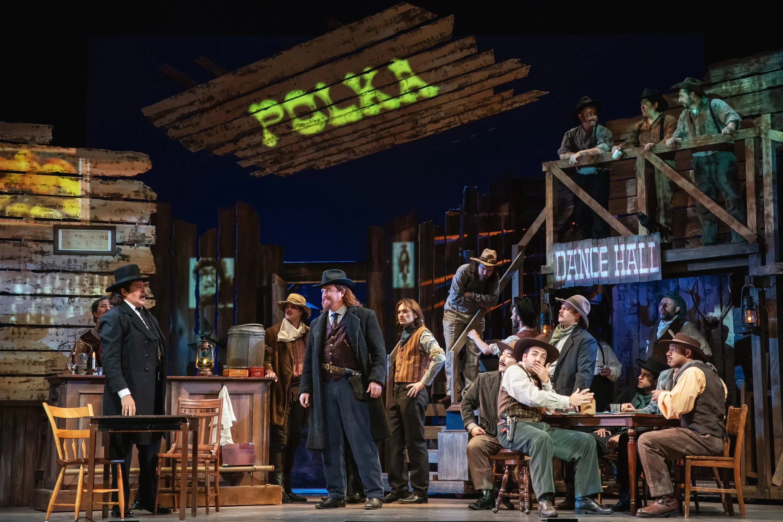 Wide-shot of the polka hall featuring the designed bar, set dressing and props for the opera “La Fanciulla del West”