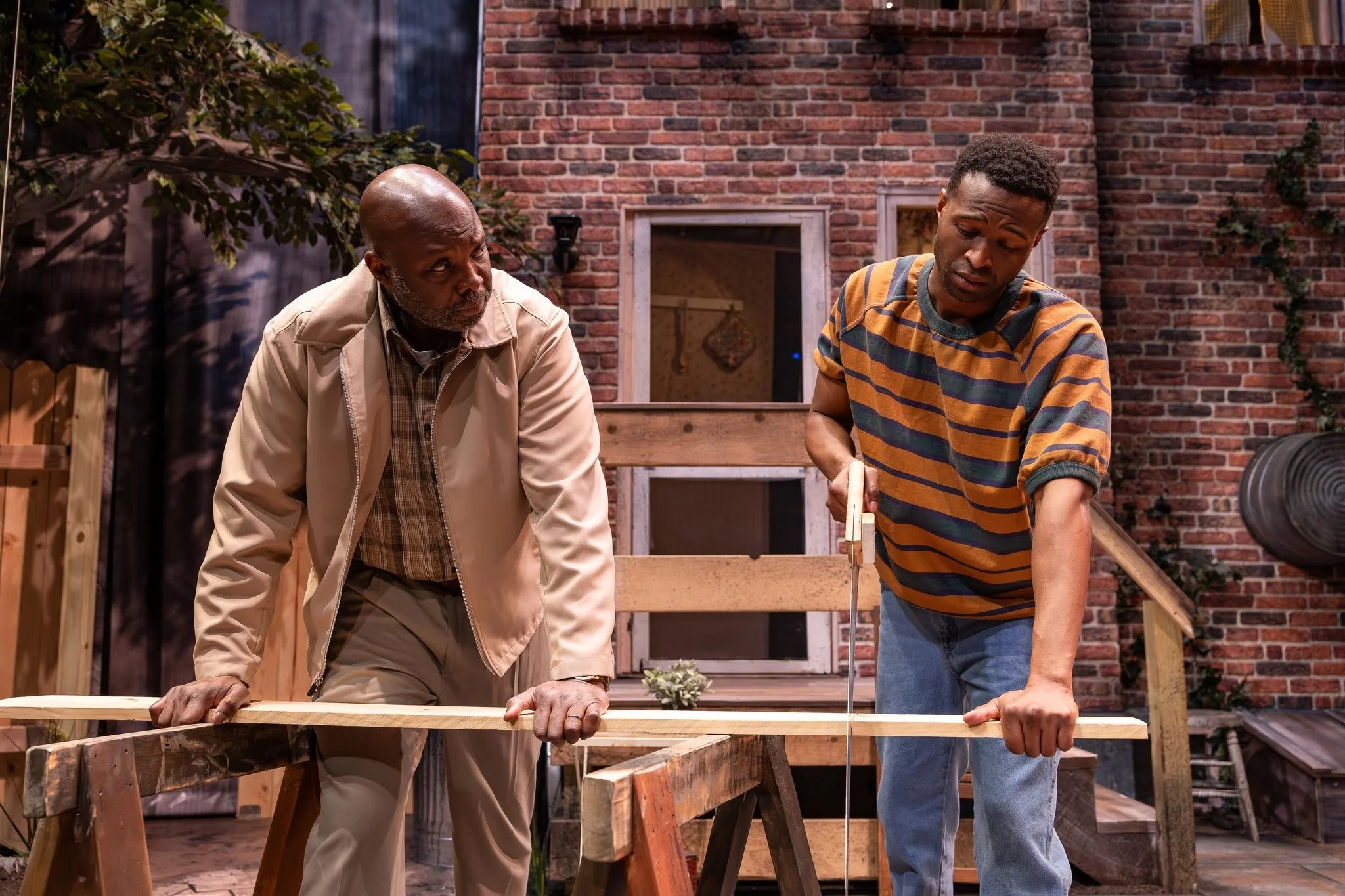 Troy and Cory cutting wood onstage in the play “Fences” by August Wilson