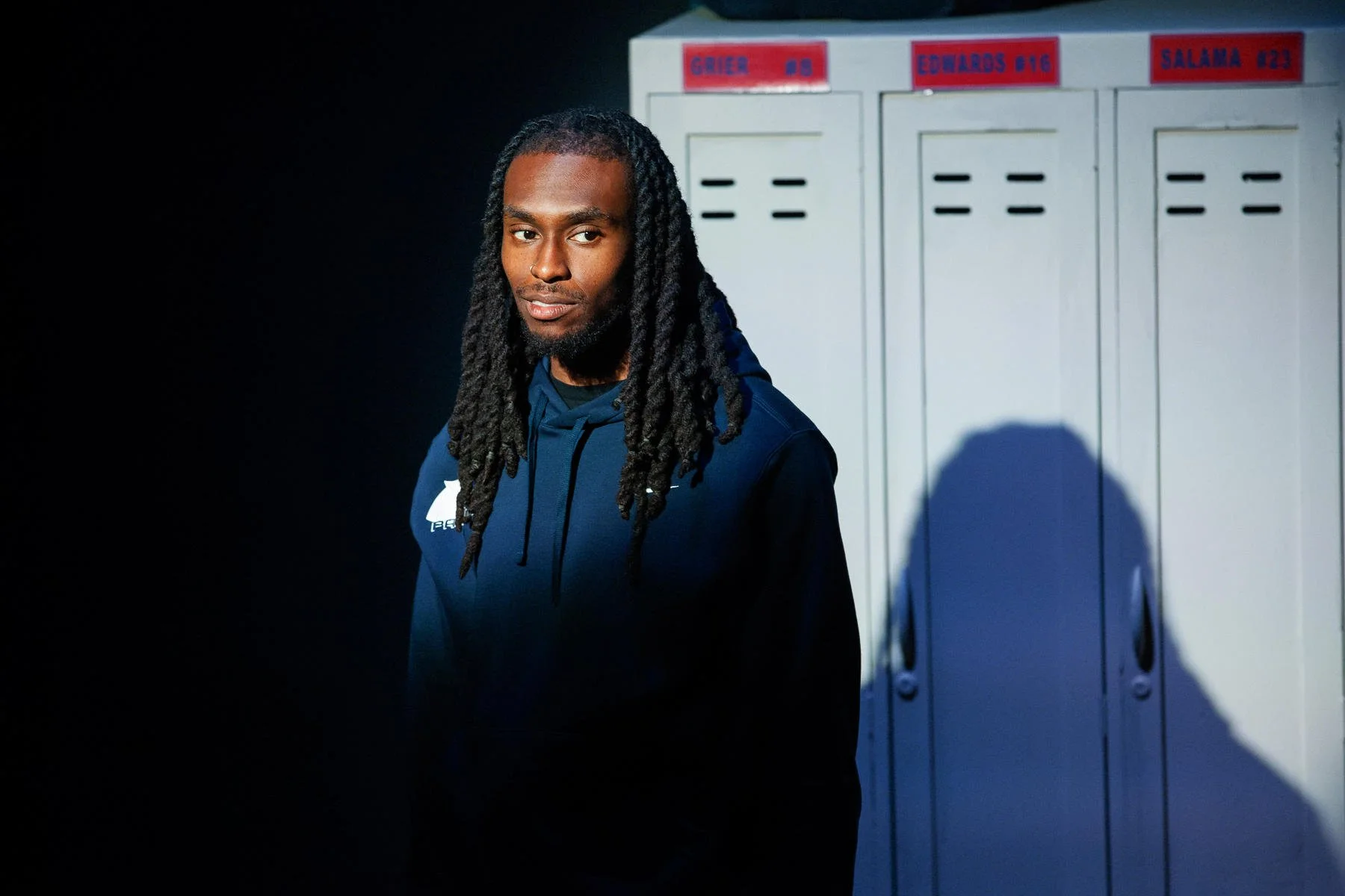 An actor standing in front of lockers in the play “American Fast” by Kareem Fahmy