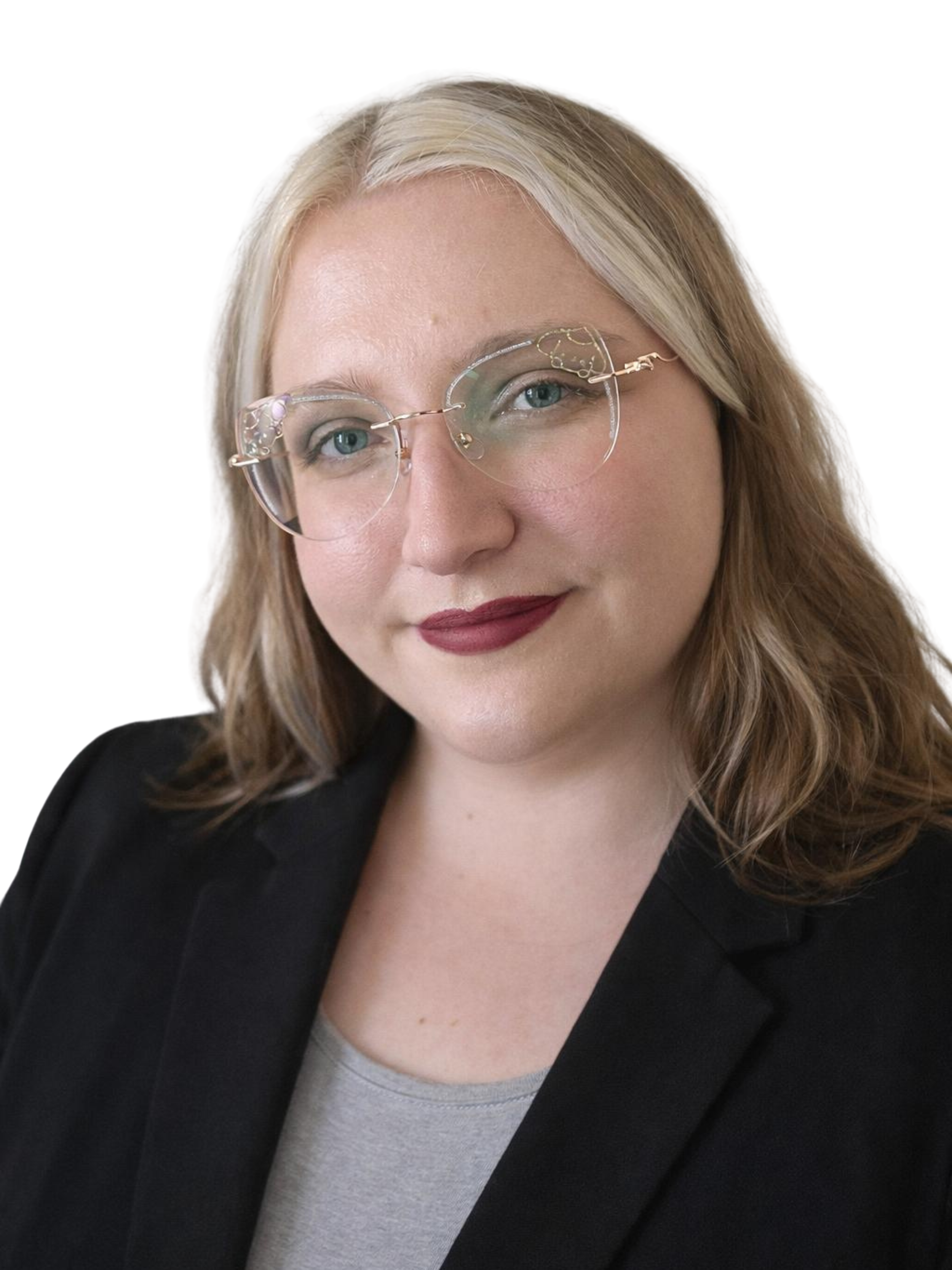 A woman with blonde hair wearing glasses, a gray shirt, and a black blazer, smiling slightly.