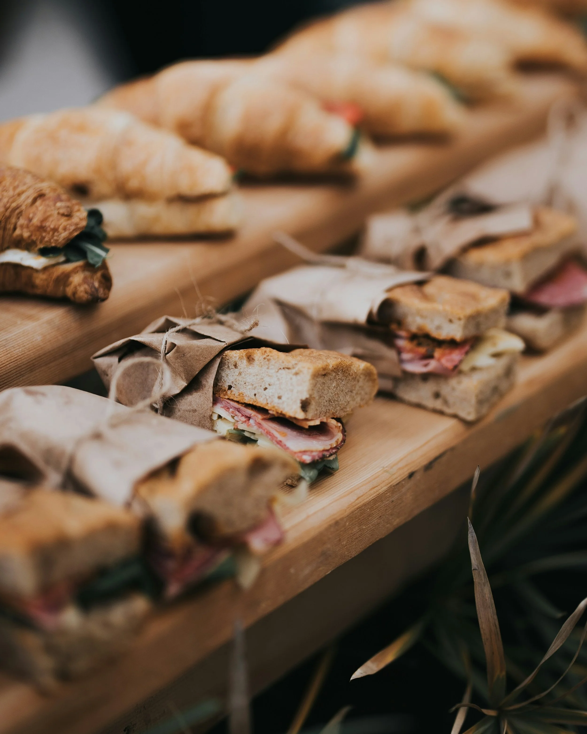 Close-up of sandwiches wrapped in brown paper and tied with string, served on a wooden surface.